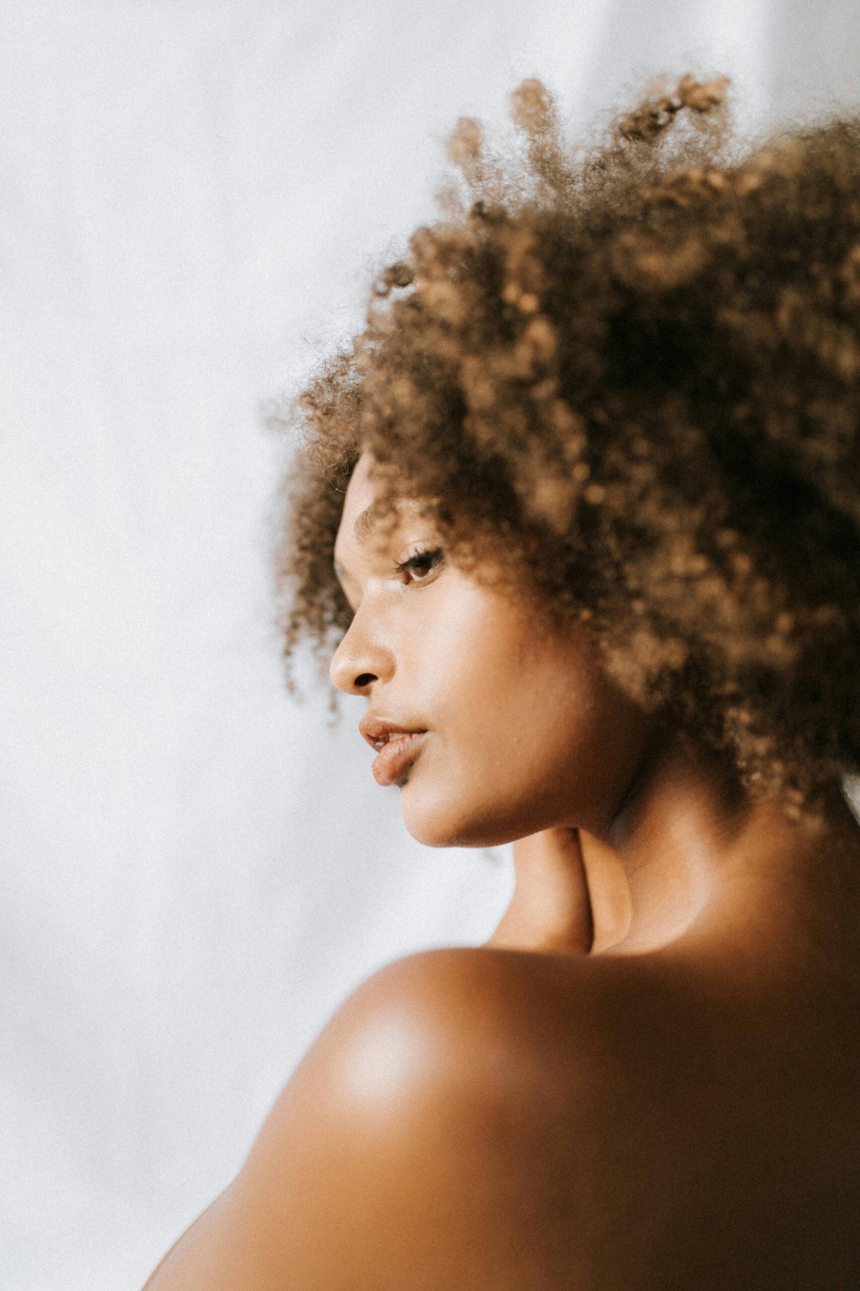 Femme avec une afro de profil touchant ses cheveux